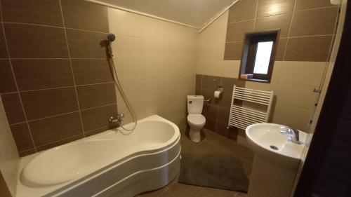 a bathroom with a tub and a toilet and a sink at Breaza - Grădina Ascunsa in Breaza