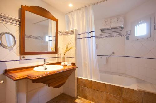 a bathroom with a sink and a tub and a mirror at Hotel Cala Sant Vicenç - Adults Only in Cala de Sant Vicent
