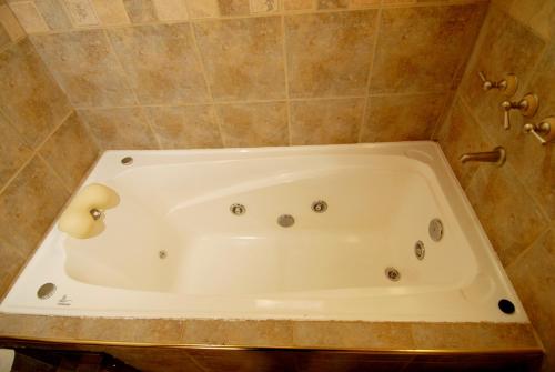a bath tub in a bathroom with a tiled wall at Cabañas Rincones del Sur in Trevelin