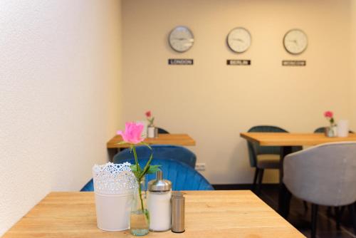 a table with two clocks on the wall and a vase with flowers at Hotel TwentyFour Living in Bad Urach