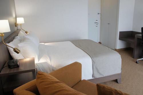 a hotel room with a bed and a chair at Hôtel Castel in Granby