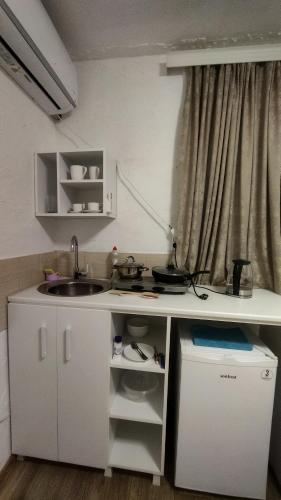 a small white kitchen with a sink and a window at Shapatava ApartHotel in Batumi