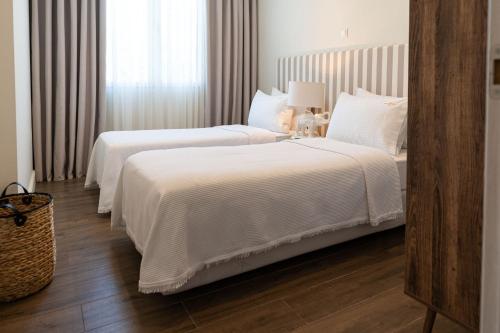 two beds in a hotel room with white sheets at Kappa Resort in Paliouri