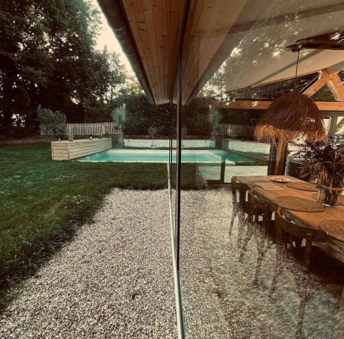 a swimming pool with a table and an umbrella at Le loft Normand avec piscine chauffée in Saint-Antonin-de-Sommaire