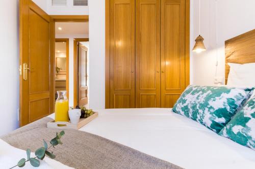 1 dormitorio con 1 cama blanca grande y armarios de madera en MARIA ZAMBRANO PREMIUM, en Málaga