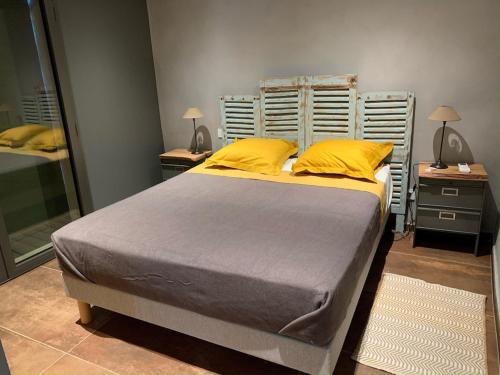 une chambre avec un grand lit avec des oreillers jaunes dans l'établissement Villa le Grangeon à Caromb, à Caromb