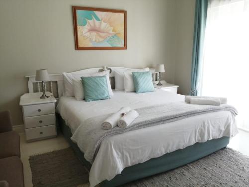 a bedroom with a large white bed with towels on it at Summer House in Hermanus