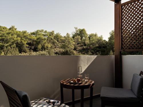 a table and chairs on a balcony with a view of trees at Lindian Village All Inclusive Resort Rhodes,Curio Collection in Kiotari