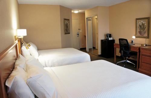 a hotel room with two beds and a desk at Hôtel Castel in Granby