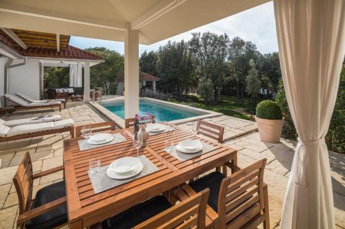a dining table and chairs on a patio with a pool at Luxury Glamping Beach Villas Porto Bus in Bale