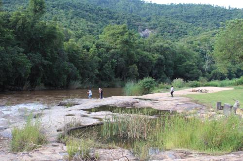 a group of people standing on a rock near a river at Lions Rock Rapids - Luxury Tented Camp in Hazyview