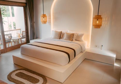 una camera da letto con un letto bianco con una panca intorno di Sanjula Uluwatu a Uluwatu