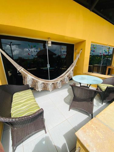 a patio with a hammock and chairs and a table at Wintervilleflat904 in Gravatá