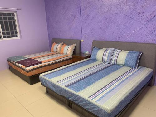 two beds in a room with purple walls at Fangliao Homestay in Fangliao