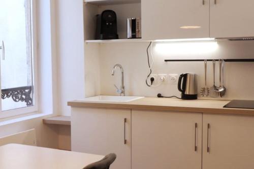 a kitchen with white cabinets and a sink and a window at Le Doux Refuge à quelques pas de la Cathédrale in Chartres