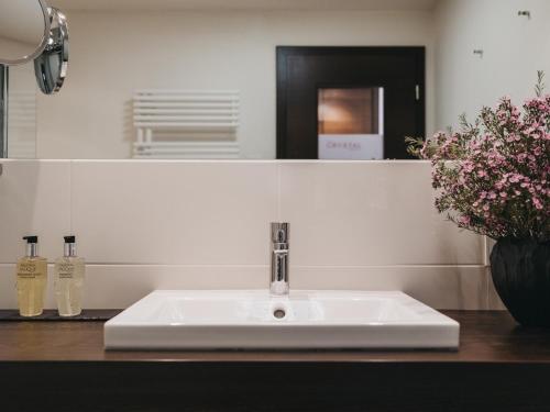 a white sink in a bathroom with flowers on a counter at The Crystal VAYA Unique in Obergurgl