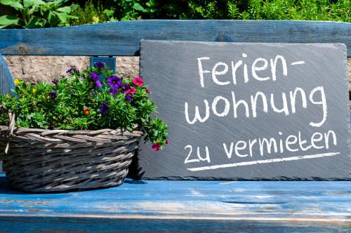 a sign sitting on a bench with a basket of flowers at GreenLeaf Walhalla-Apartment - Highspeed WLAN - Netflix - Südbalkon in Tegernheim