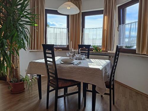 a dining room with a table with chairs and windows at Ferienwohnung Sonne in Bad Windsheim