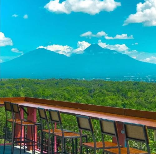 a row of chairs on a balcony with a view of mountains at Rajaklana Resort and Spa in Bantul