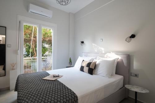a white bedroom with a large bed and a window at apt Eleven - cozy apartment with garden in Athens