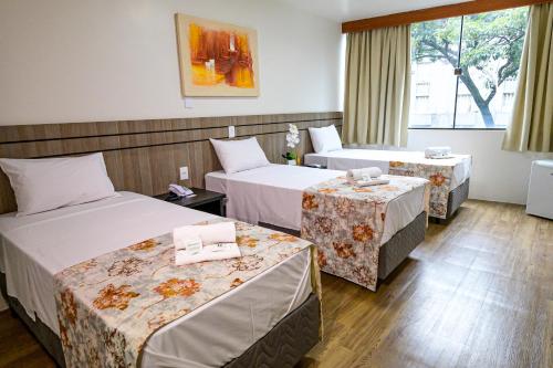 a hotel room with two beds and two tables at Hotel Nacional Inn São Paulo - Próximo ao COPAN in São Paulo