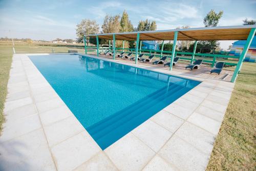 a swimming pool with a pavilion and chairs around it at La Chakana de Uribelarrea in Uribelarrea