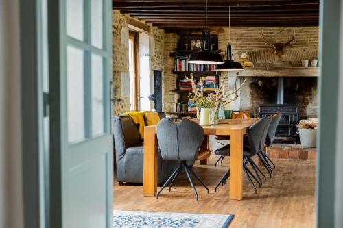 een kamer met een tafel en stoelen en een open haard bij Chambres d'hôtes Maison Les Galettes in Rezay