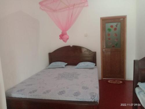 a bedroom with a bed with a pink umbrella at Ancient Tree in Mirissa