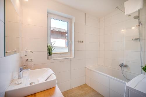 a white bathroom with a sink and a bath tub at Haus Ottilia - Top 5 in Neukirchen am Großvenediger