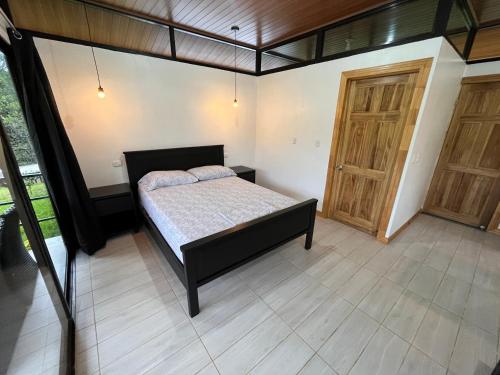 a bedroom with a bed and a wooden door at Pacheco Tours Rainforest Cabins in Drake