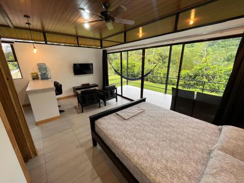 1 dormitorio con cama y ventana grande en Pacheco Tours Rainforest Cabins, en Drake