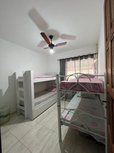 Zimmer mit 2 Etagenbetten und einem Deckenventilator. in der Unterkunft Nosso Repouso Saquarema - Casa inteira com Piscina,churrasqueira privativos, Wi-fi,900m da praia, Tv-Smart. in Saquarema