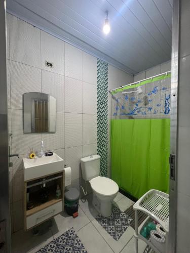 a bathroom with a toilet and a green shower curtain at Nosso Repouso Saquarema - Casa inteira com Piscina,churrasqueira privativos, Wi-fi,900m da praia, Tv-Smart. in Saquarema