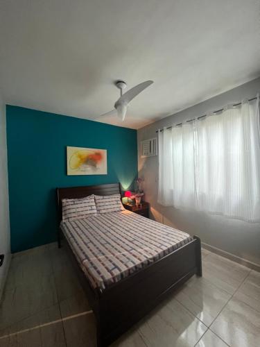 1 dormitorio con cama y pared azul en Nosso Repouso Saquarema - Casa inteira com Piscina,churrasqueira privativos, Wi-fi,900m da praia, Tv-Smart. en Saquarema
