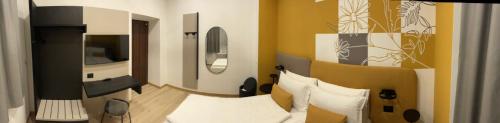 a bedroom with a bed with white pillows and a television at House of Bruno - Only self check-in in Trento