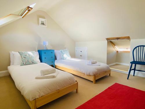 a bedroom with two beds and a blue chair at Blackford House a large home Portland Dorset in Portland