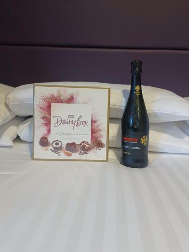 a bottle of wine on a bed next to a box at Ravelston House in Musselburgh