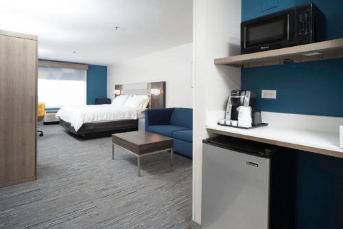 a hotel room with a bed and a room with a kitchen at Holiday Inn Express and Suites Atlanta-Johns Creek by IHG in Johns Creek