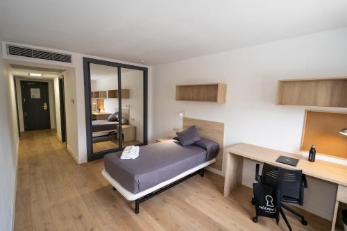 a bedroom with a bed and a desk and a desk at Micampus Leganés Student Residence in Leganés