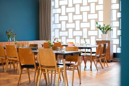 a dining room with tables and chairs and a wall at magdas HOTEL Vienna City - First Social Business HOTEL in Austria in Vienna