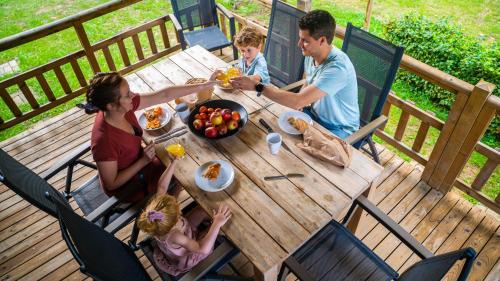 a family eating at a wooden table on a deck at EuroParcs Kohnenhof in Obereisenbach