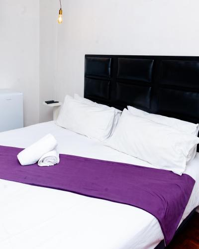 a large bed with a purple blanket and white pillows at Nkosazana Guest House in Durban
