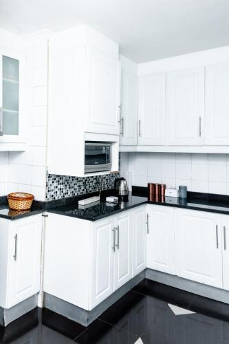 a white kitchen with white cabinets and black counter tops at Nkosazana Guest House in Durban