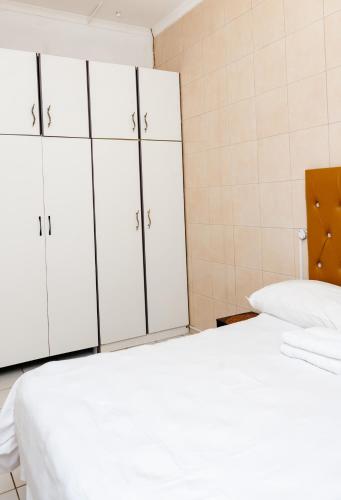a bedroom with white cabinets and a white bed at Nkosazana Guest House in Durban