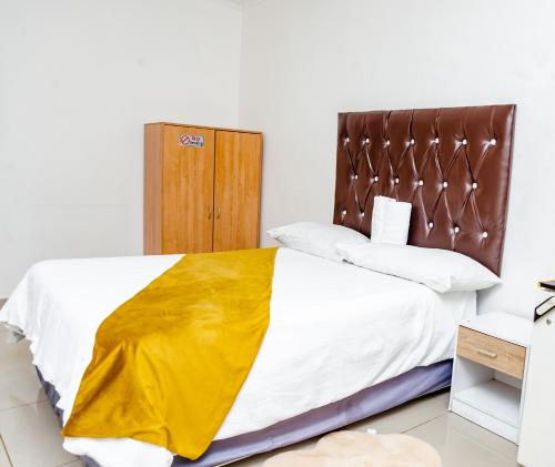 a bedroom with a bed with white sheets and yellow blanket at Nkosazana Guest House in Durban