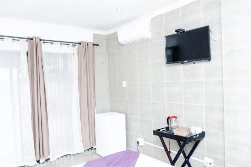 a bathroom with a television on a tiled wall at Nkosazana Guest House in Durban