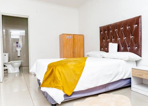 a bedroom with a bed with a yellow blanket on it at Nkosazana Guest House in Durban