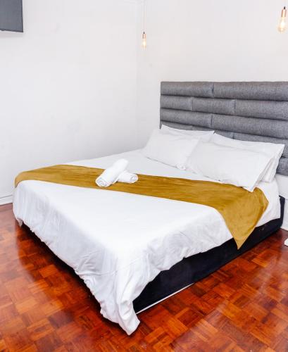 a bedroom with a large bed with white sheets at Nkosazana Guest House in Durban