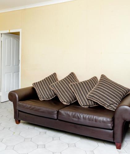 a brown leather couch with three pillows on it at Nkosazana Guest House in Durban