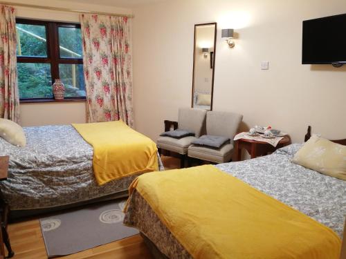 a hotel room with two beds and a chair at Ben View Guesthouse in Clifden